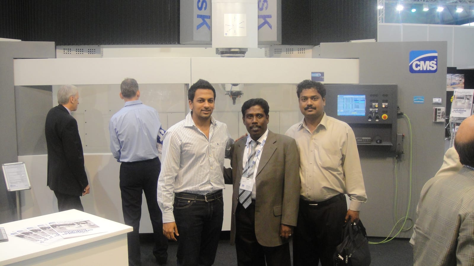 ABS India team in front of a CMS machining center on the CMS stand, EMO Milan 2009